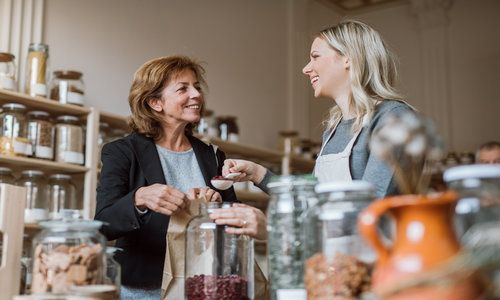 Female Shop Assistant Serving a Senior Customer in a Zero-Waste Shop.