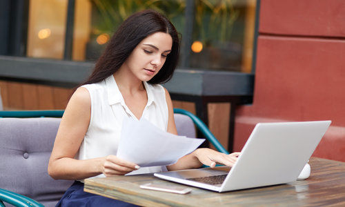 Serious female company owner concentrated into documents, reads attentively terms of contract.